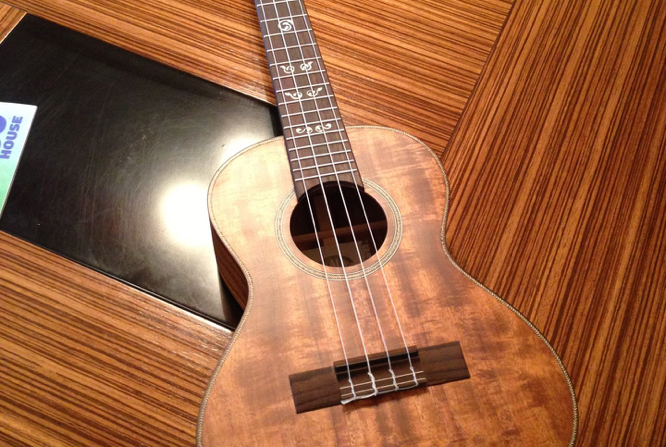 A wooden ukulele resting on a wood-grain table